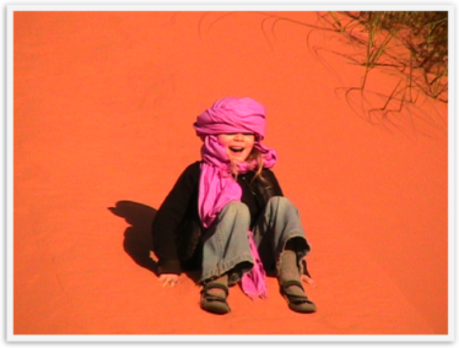 Travel kid Mozart in the Sahara sliding down a dune laughing Travel kid Mozart in the Sahara sliding down a dune laughing